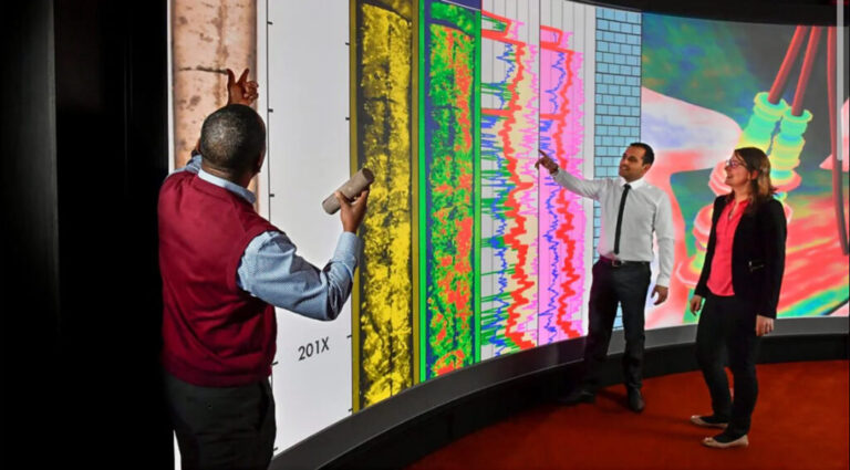 Three professionals analyzing geological data on a large digital screen