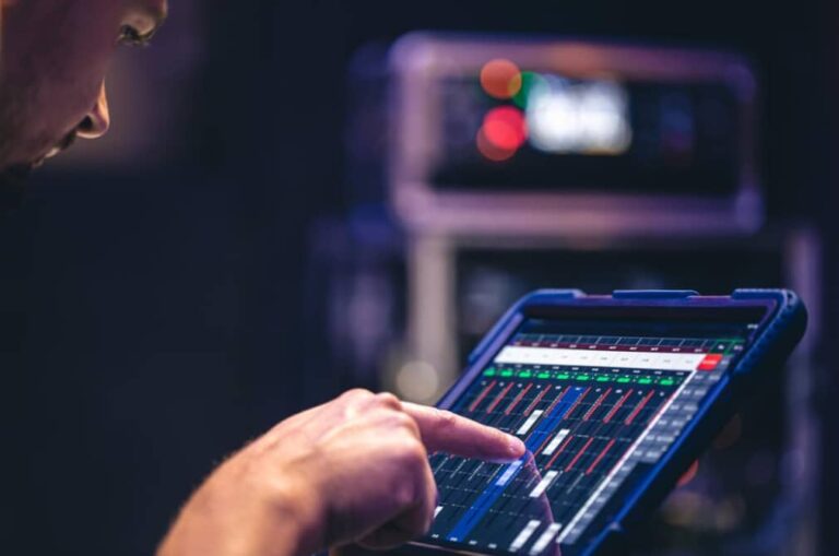 A person fine-tuning a digital audio mixer on a tablet