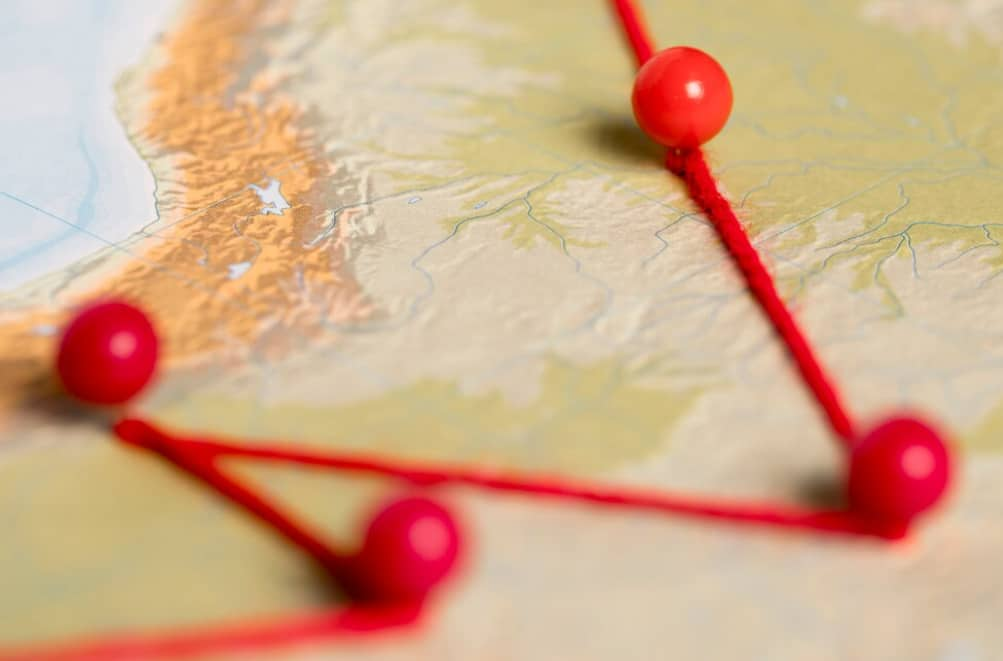 A close-up of a map with pins connected by red string